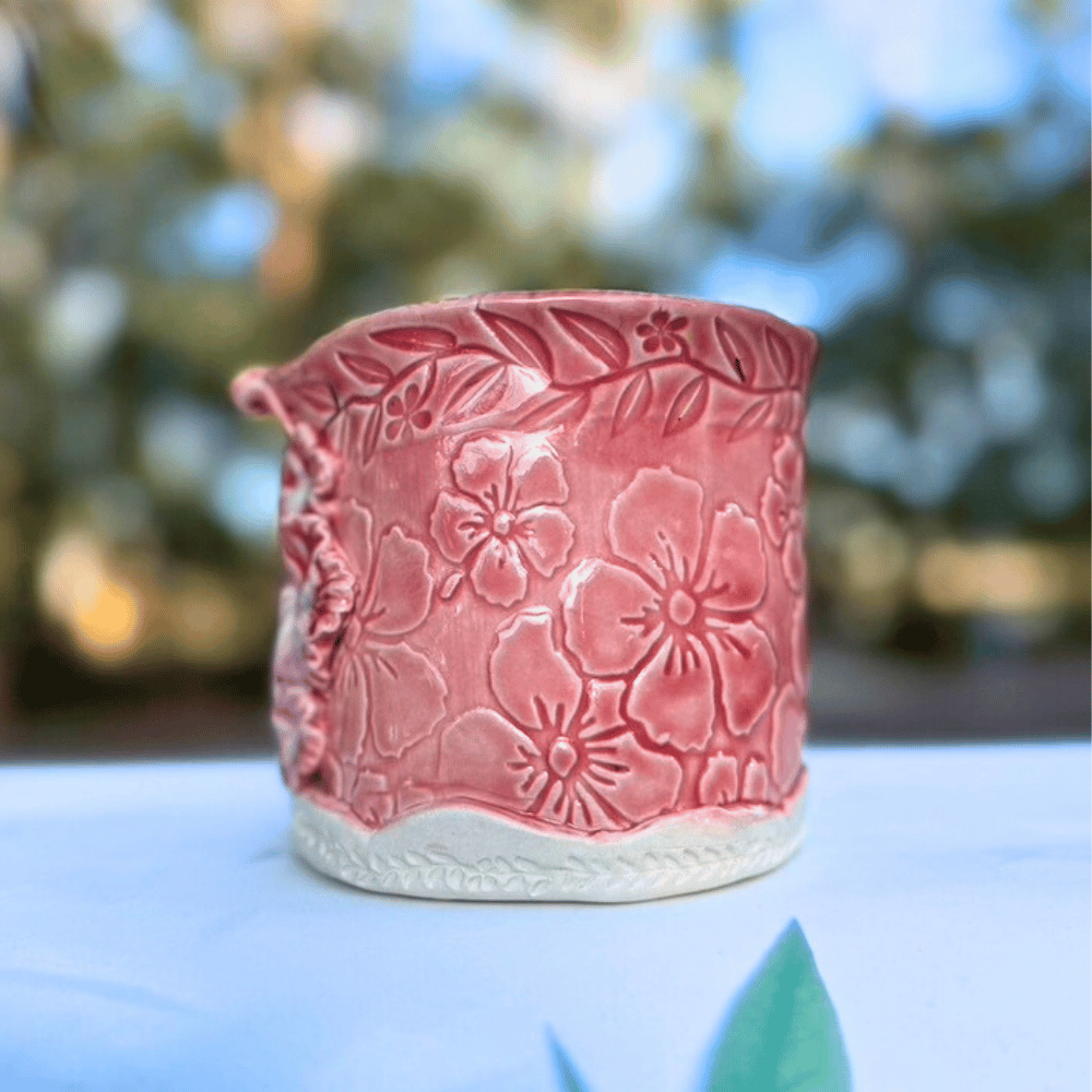 Pink ceramic planter with floral patterns on a blurred natural background