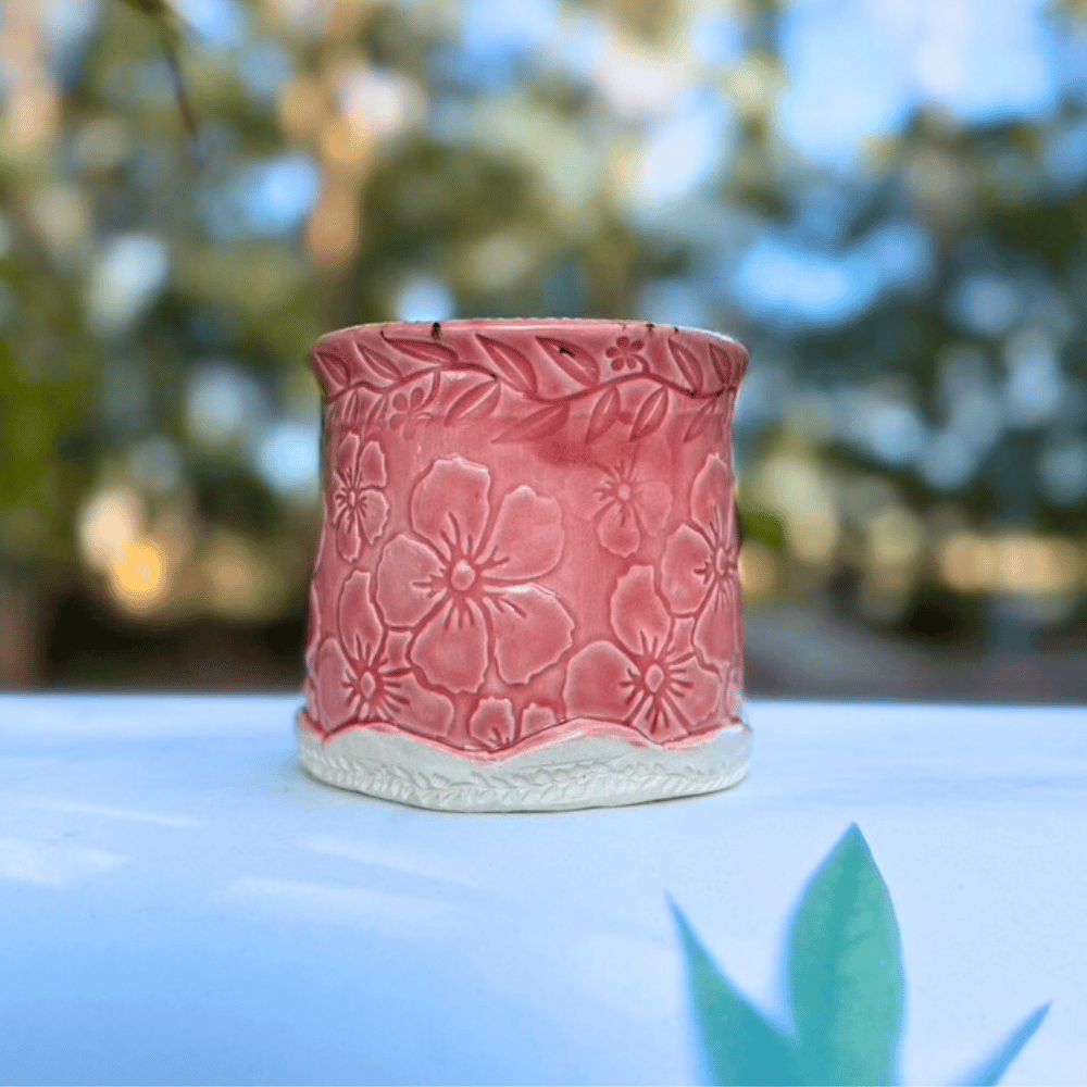 Pink ceramic pot with floral patterns on a blurred natural background
