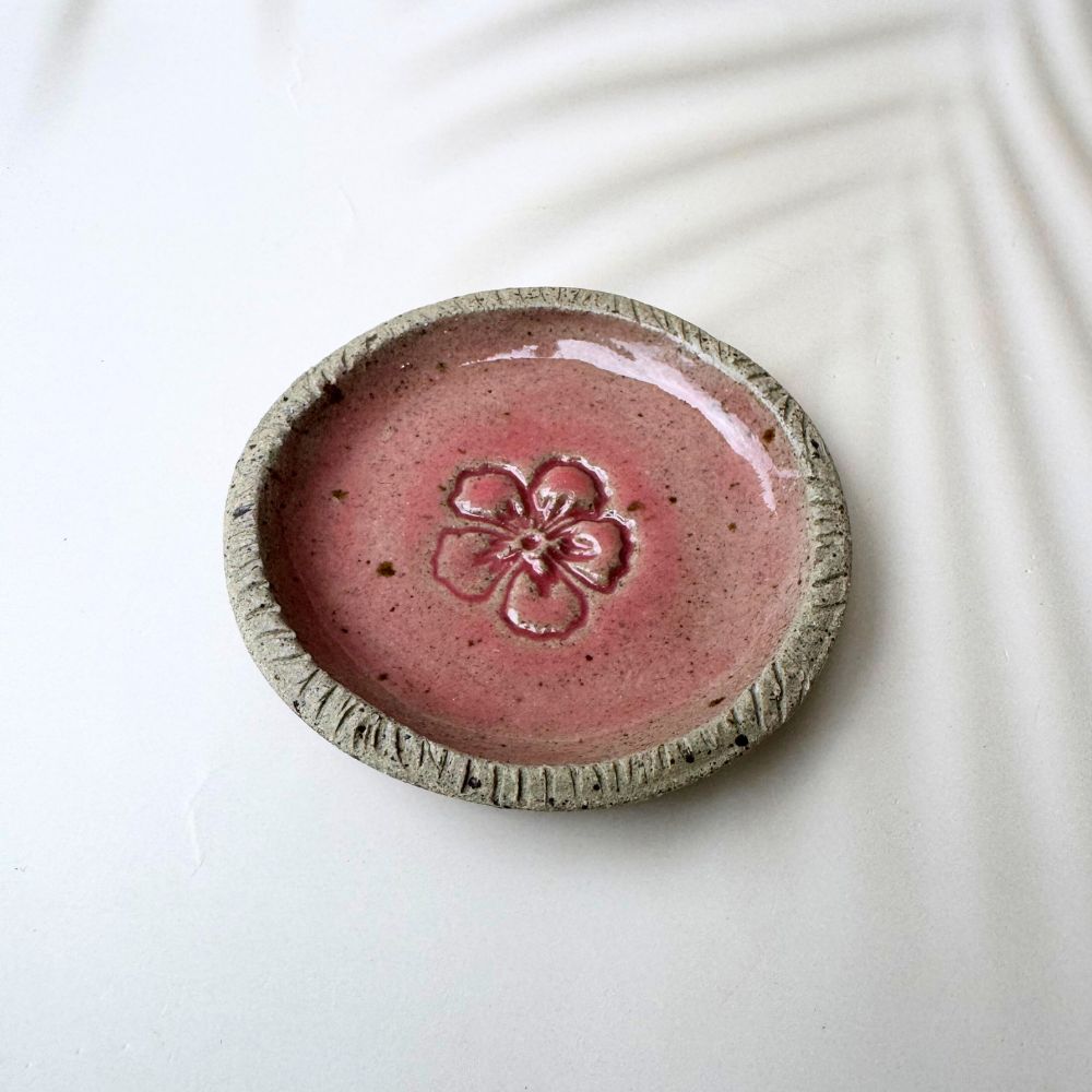 Ceramic dish with pink glaze and floral design on a white background
