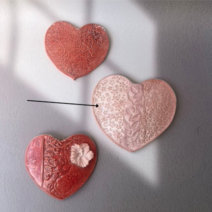 Three heart-shaped ceramic decorations on a gray background