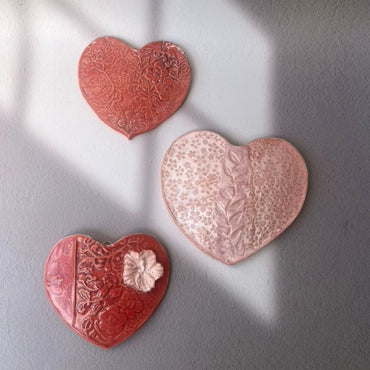 Three heart-shaped ceramic decorations on a gray background