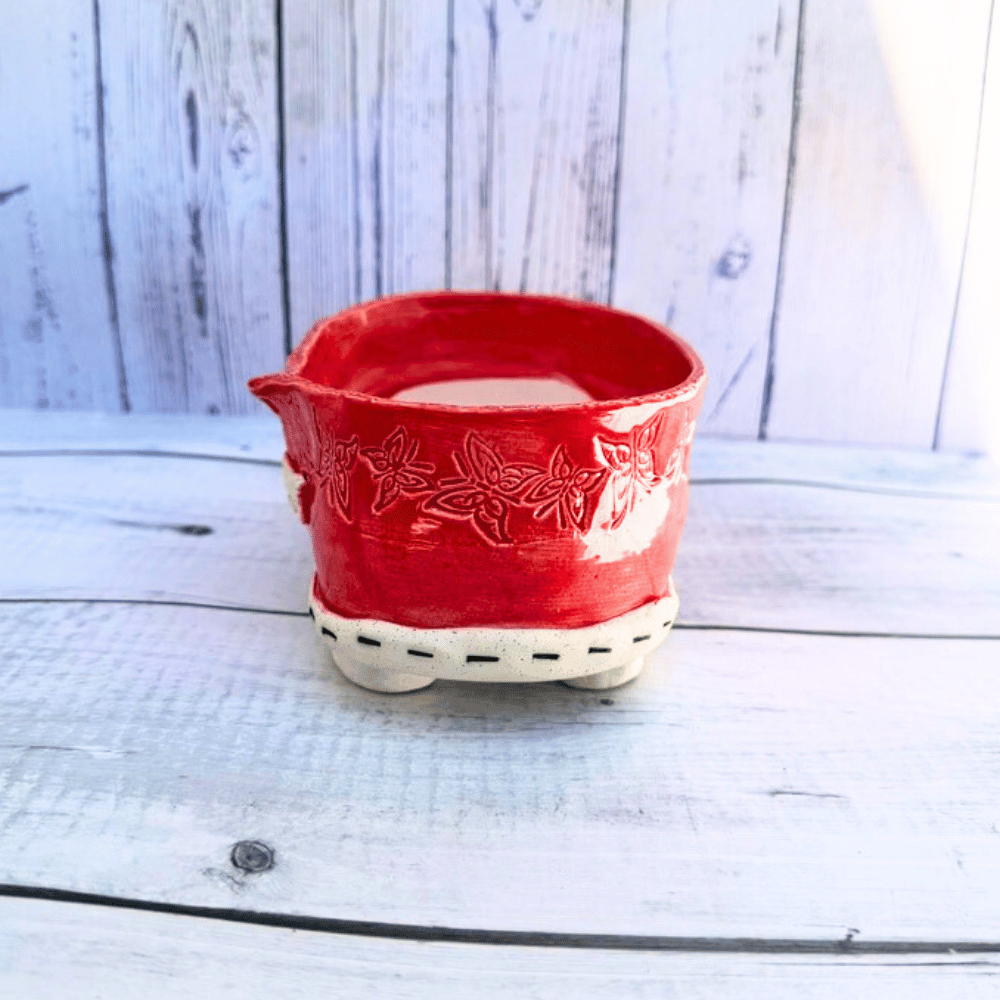 Red ceramic bowl with white interior on a wooden surface