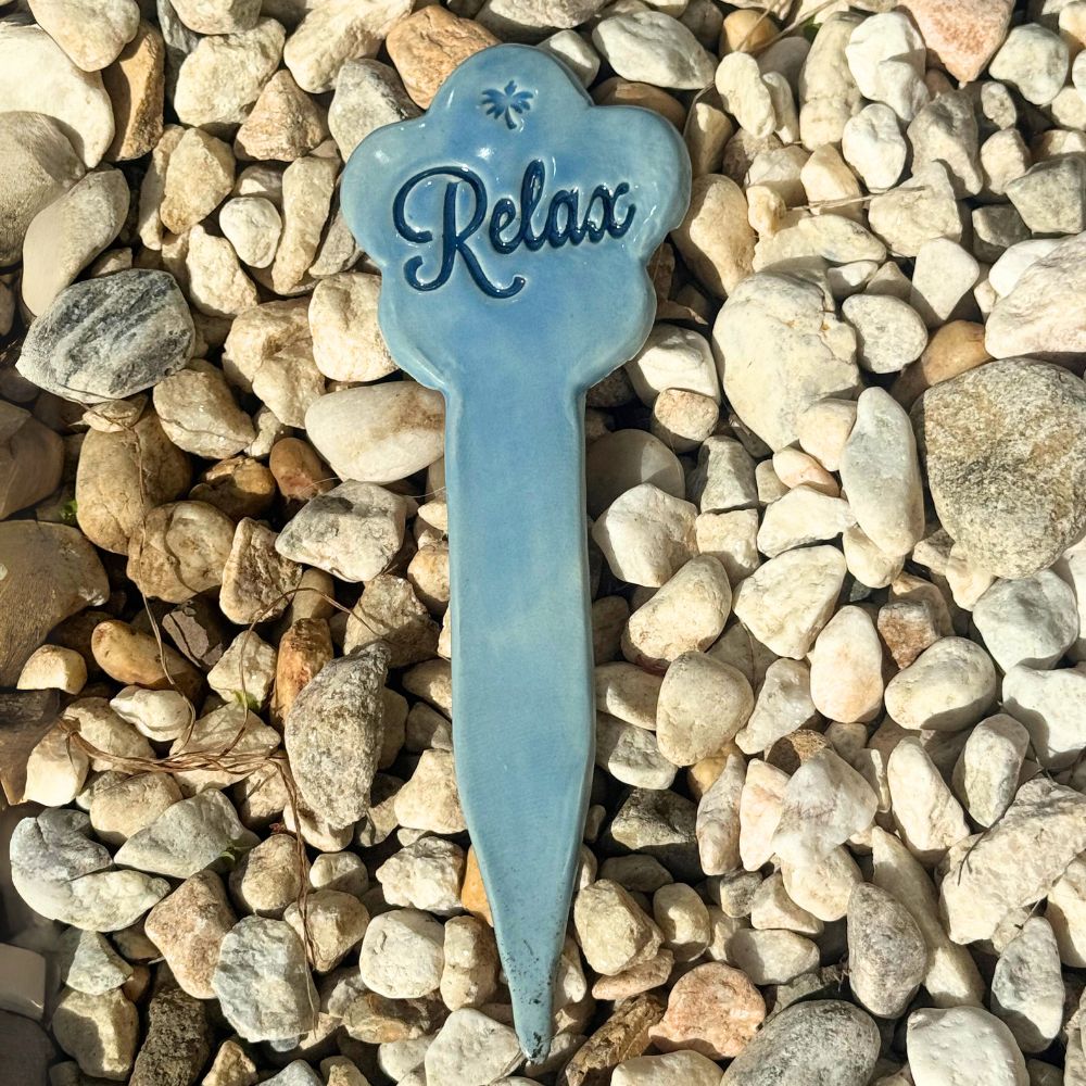 Blue 'Relax' garden stake on a bed of pebbles