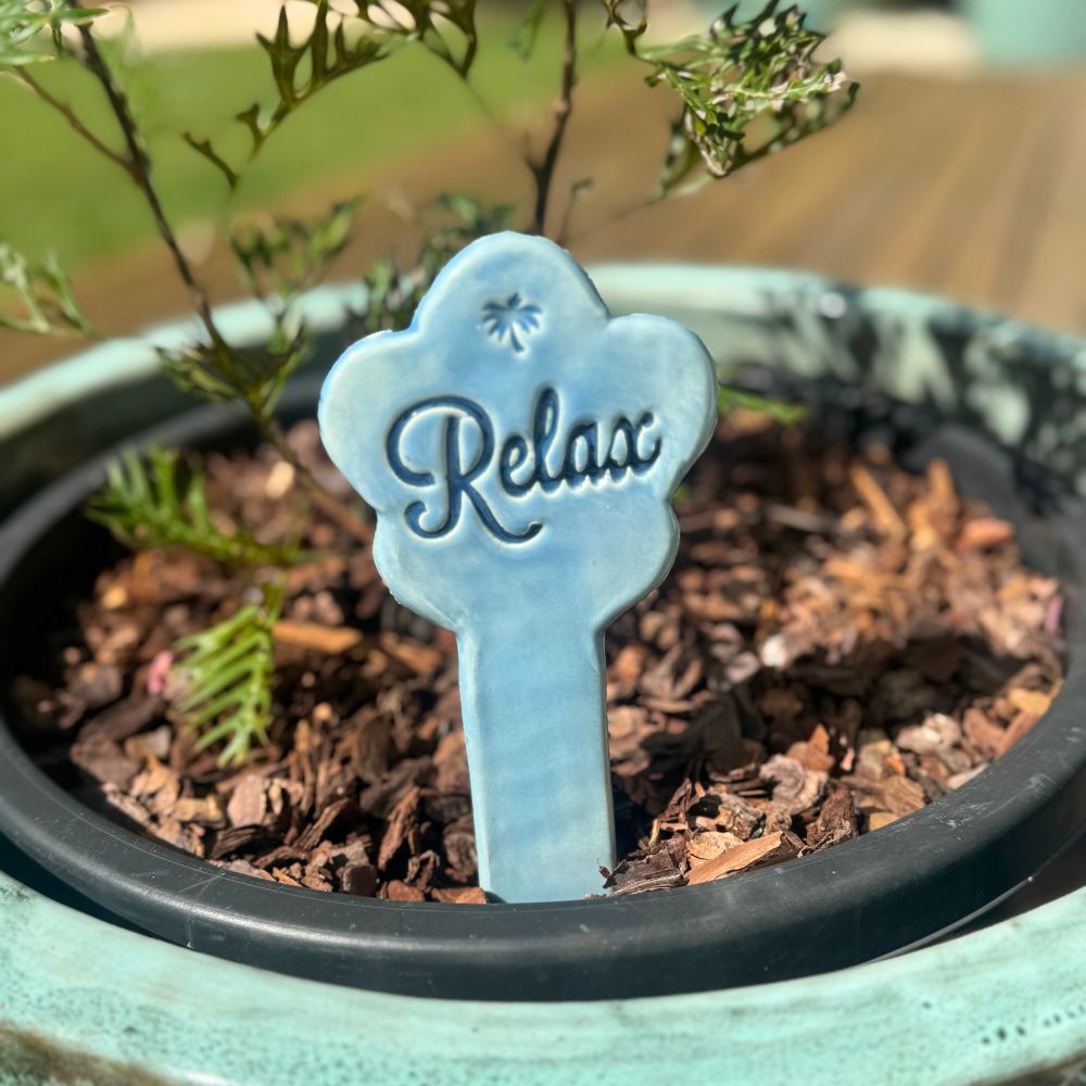 Blue 'Relax' sign in a potted plant