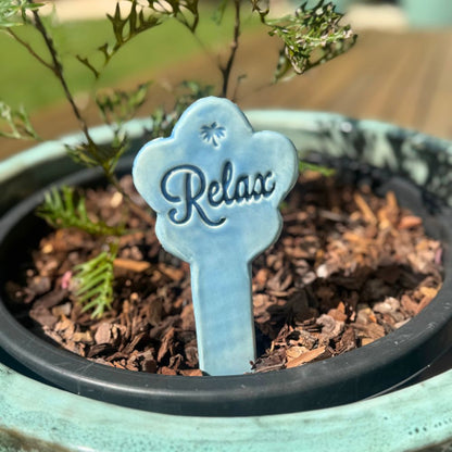 Blue 'Relax' sign in a potted plant