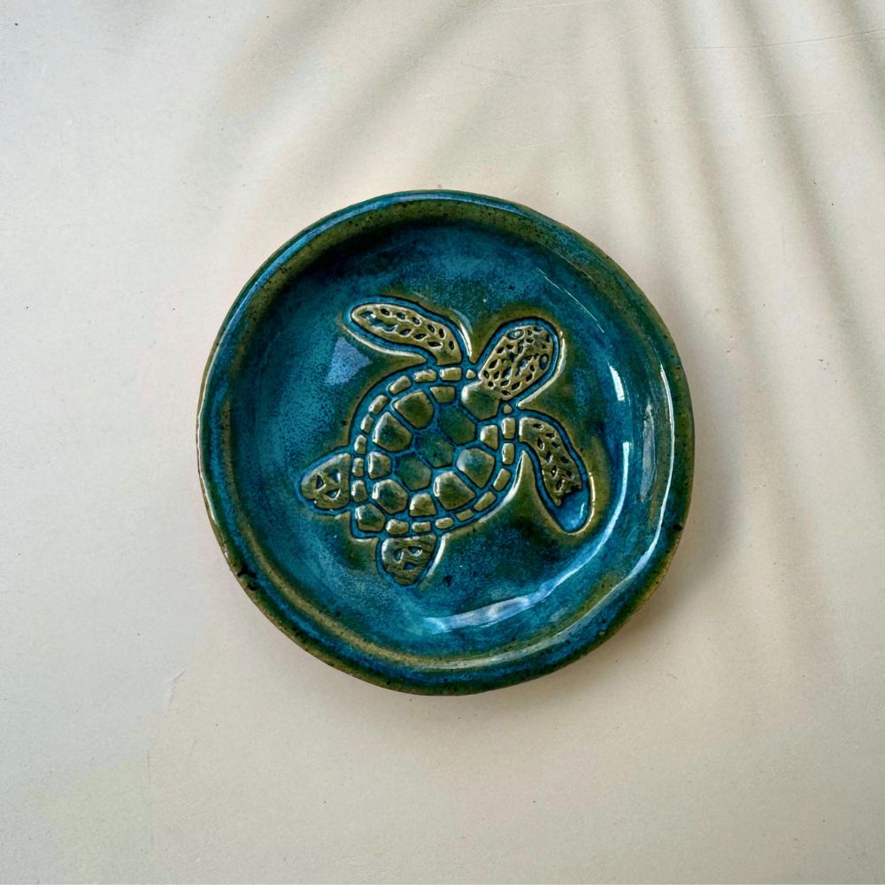 Blue ceramic dish with a turtle design on a beige background
