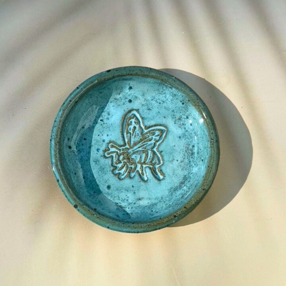 Blue ceramic dish with butterfly design on a beige surface