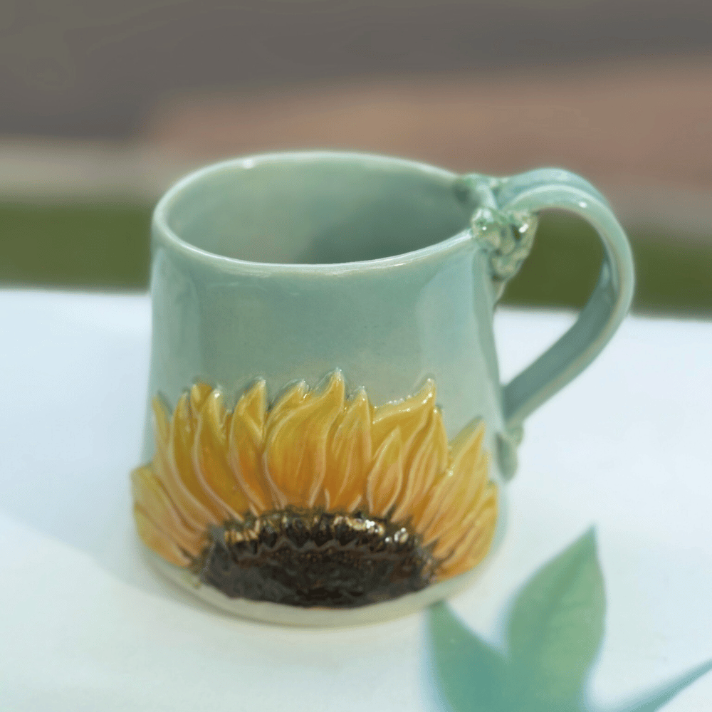 Ceramic mug with sunflower design on a white surface