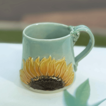 Ceramic mug with sunflower design on a white surface