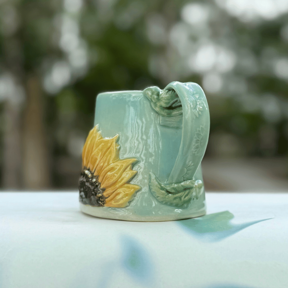 Ceramic mug with sunflower design on a blurred natural background