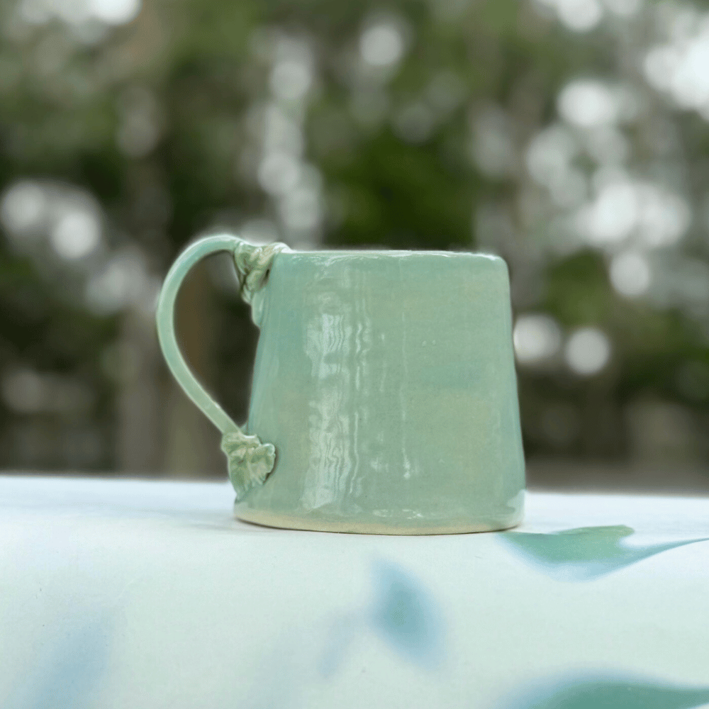 Green ceramic mug on a blurred natural background