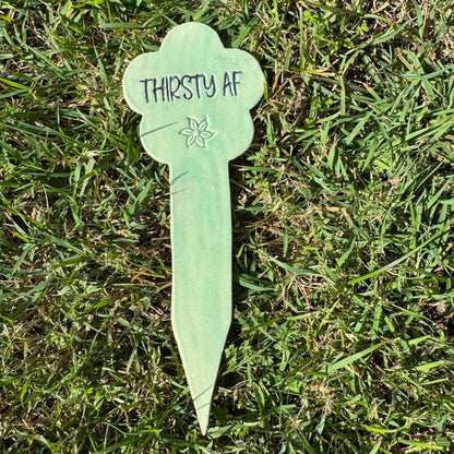Green plant label with 'THIRSTY AF' text on grass