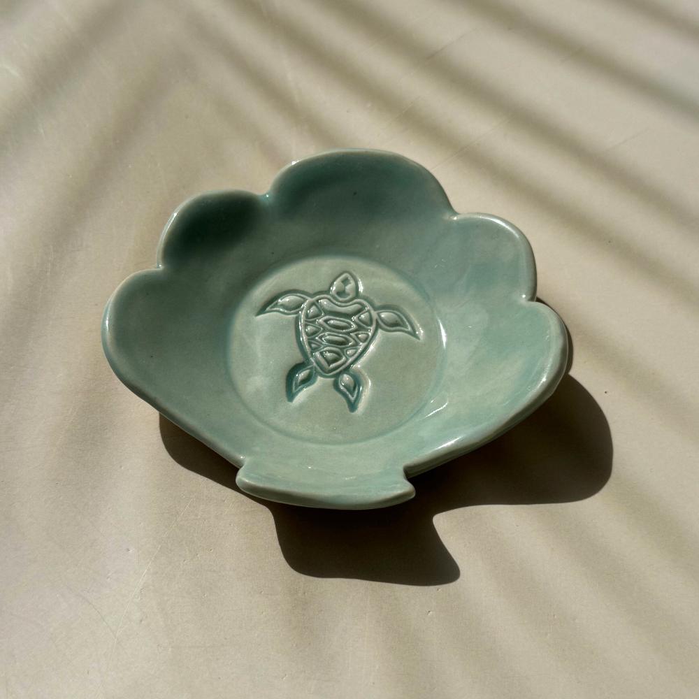 an aqua blue ceramic dish in the shape of a shell with turtle