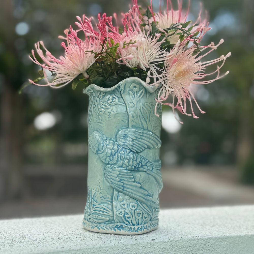 Decorative ceramic vase with bird and floral texture with floral arrangement on a blurred natural background