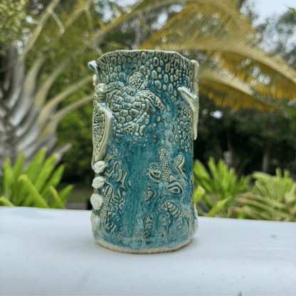 Handmade ceramic vase with turtle design against a natural background