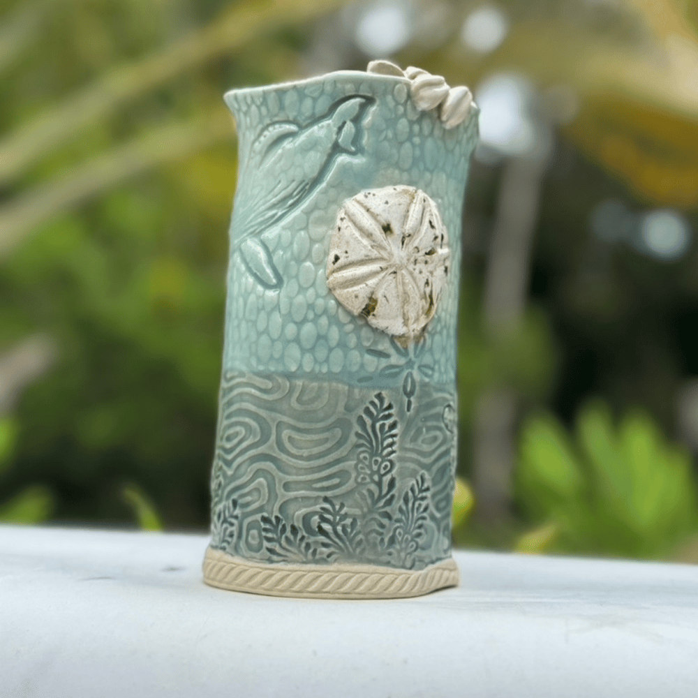 Ceramic pitcher with sand dollar design on a blurred natural background