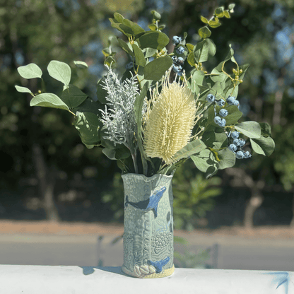Decorative whale vase with a floral arrangement against a blurred natural background