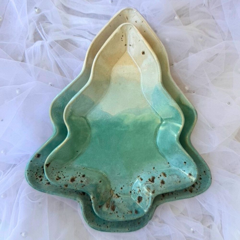 Two ceramic xmas tree plates, one larger and one smaller, on a white textured background.